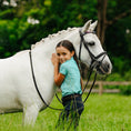 Load image into Gallery viewer, Lumiere Rainbow Bridle - child standing with a grey pony wearing the bridle

